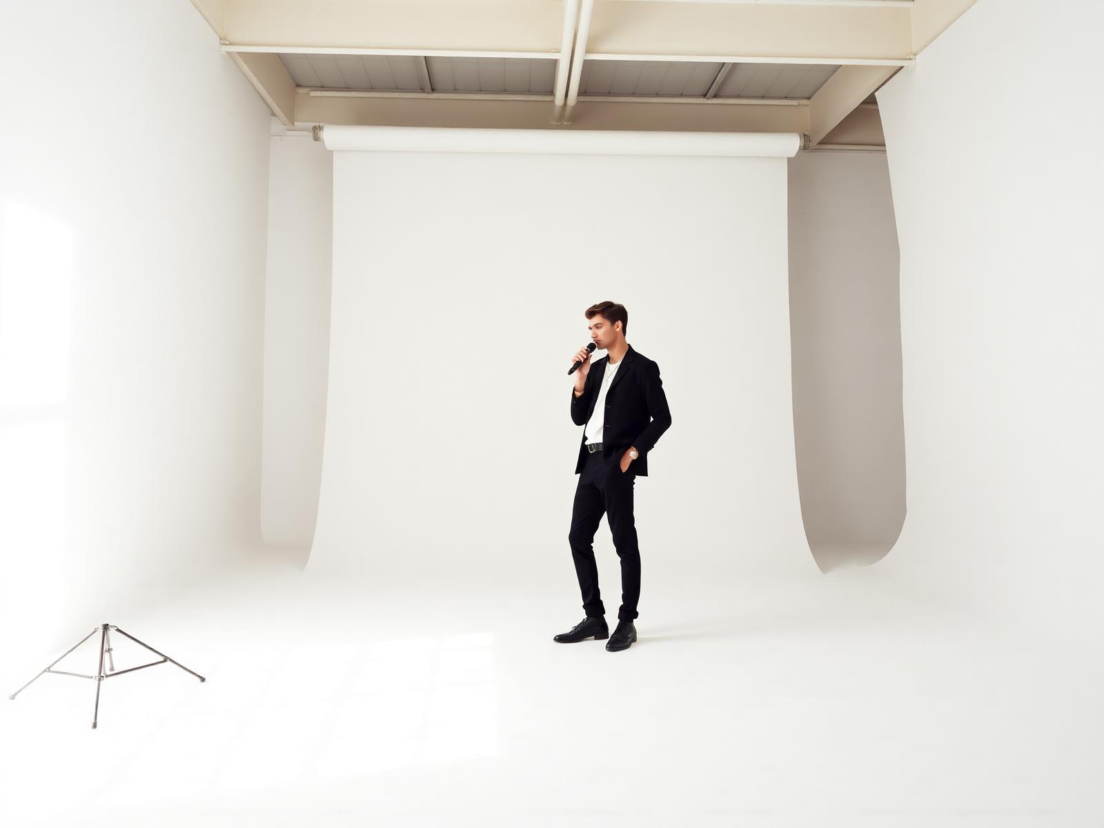 Artist standing with a microphone in a bright empty studio